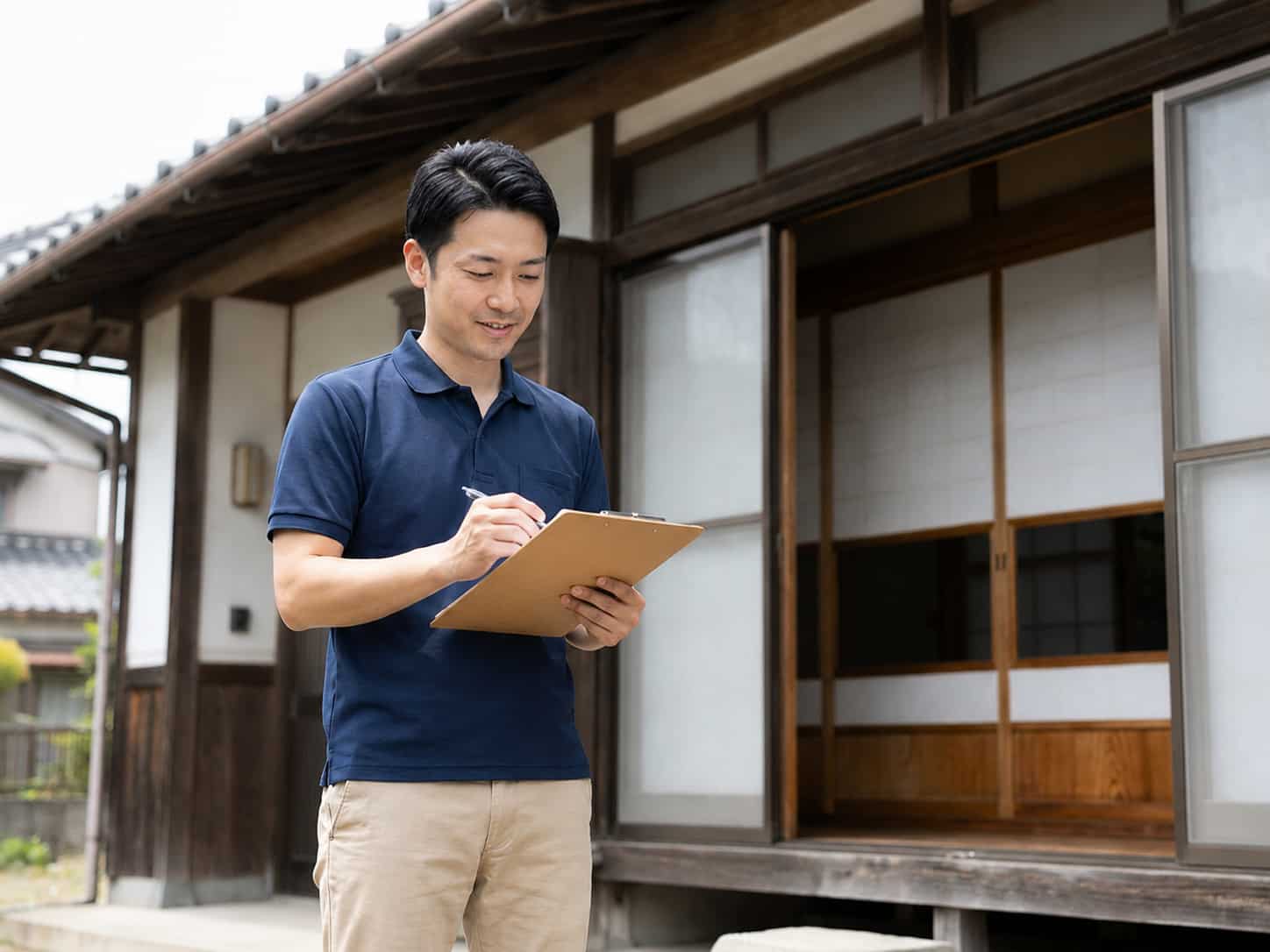 担当スタッフが日本家屋の外観をクリップボードで点検している様子
